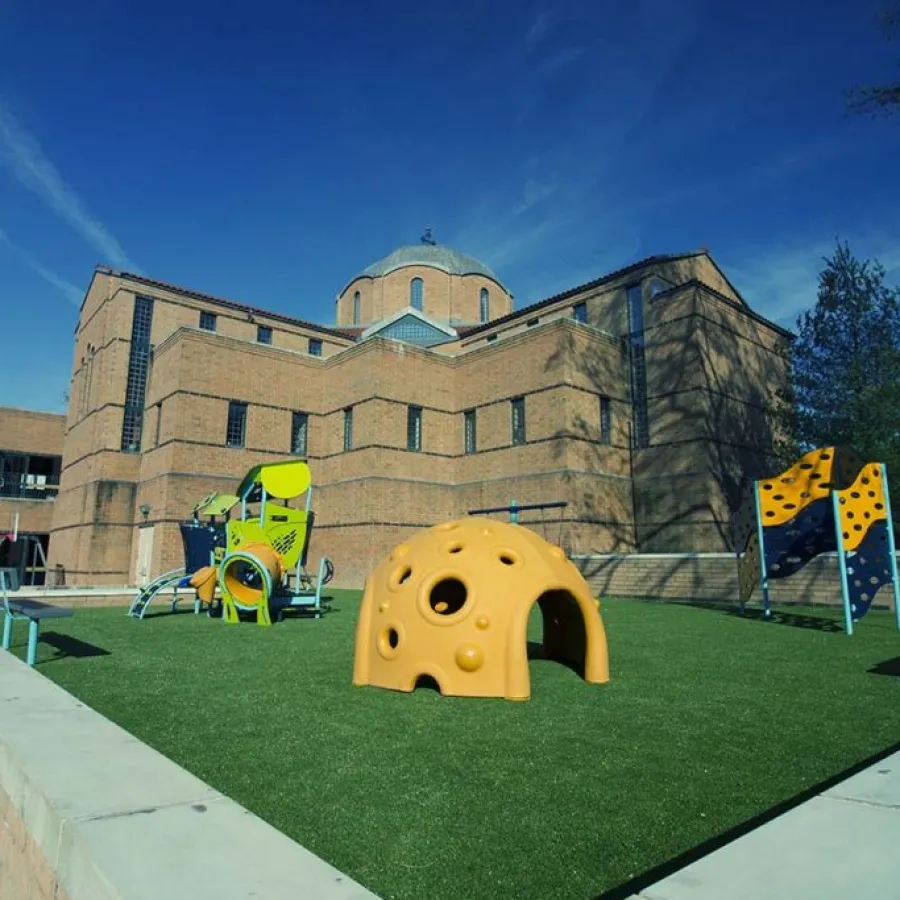 a large building with a lawn and a playground in front of it