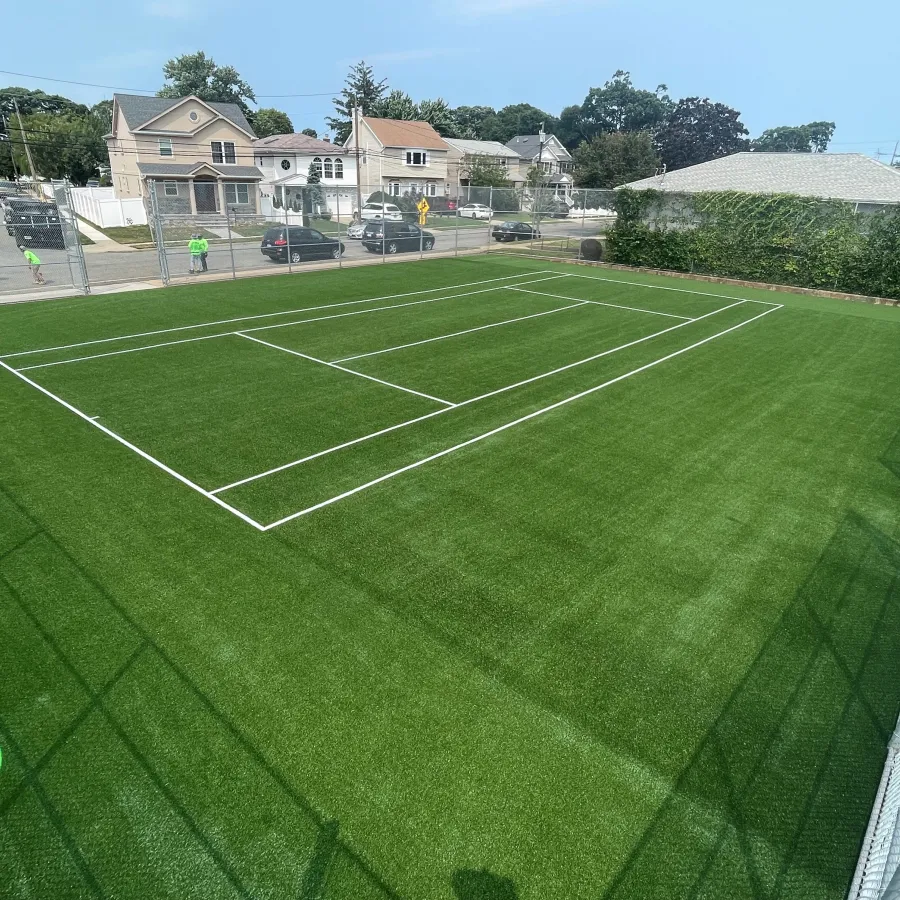 a green field with a fence and a building in the background