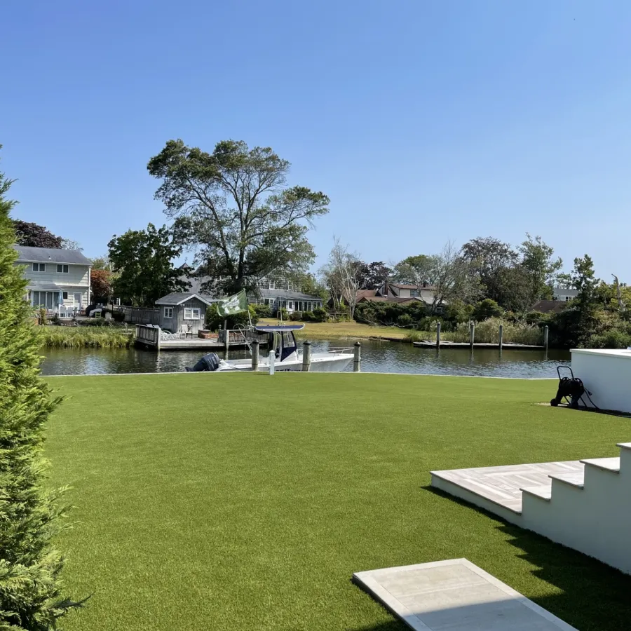a lawn with a pond and a house in the background