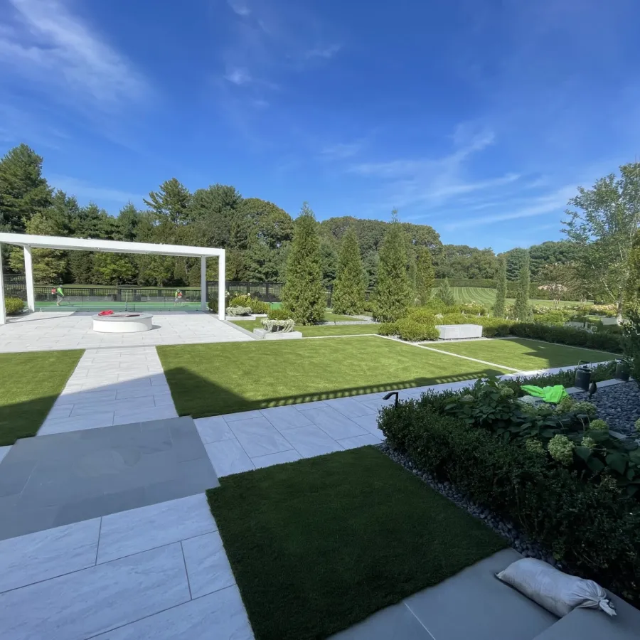 a large green lawn with a white gazebo and trees