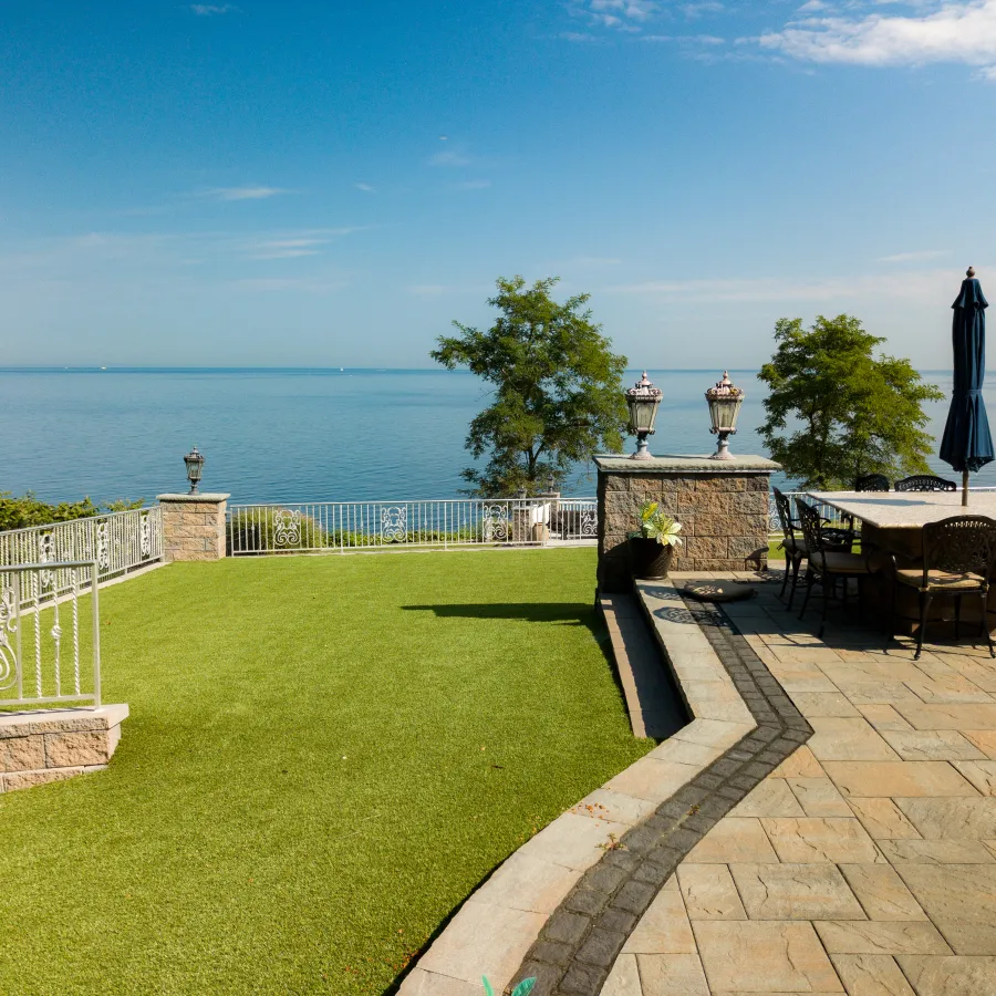 a patio with tables and chairs and umbrellas by a body of water