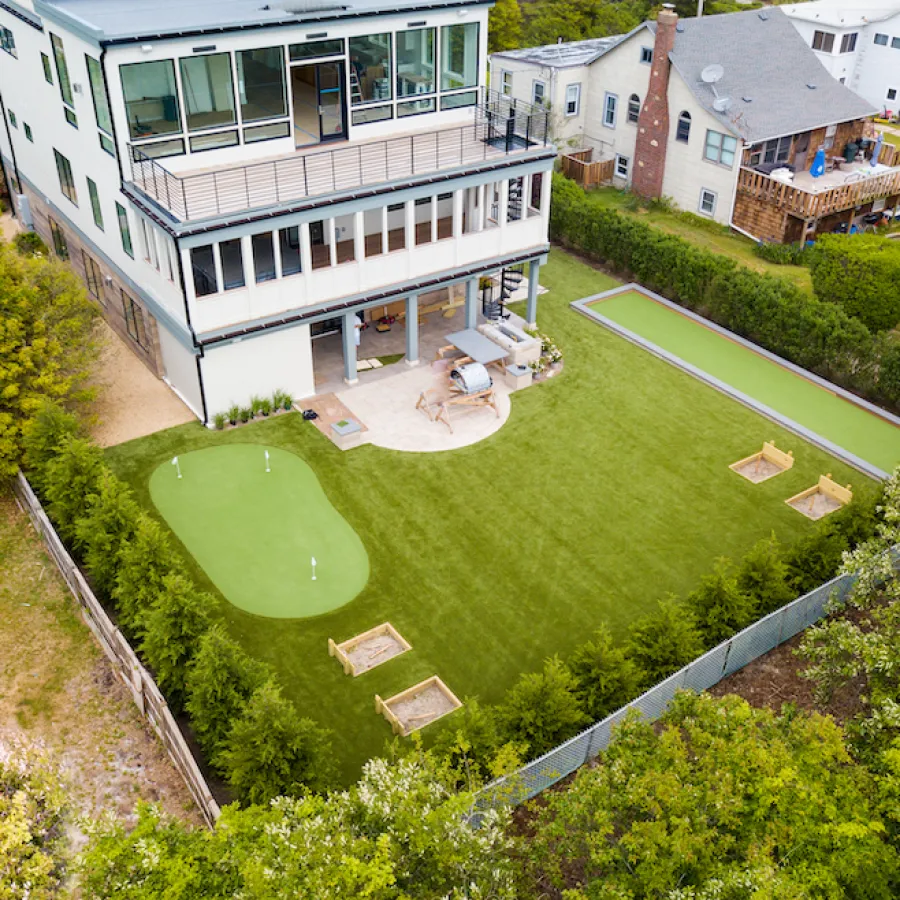 Modern house with a large backyard featuring a putting green, bocce ball court, and outdoor seating area.