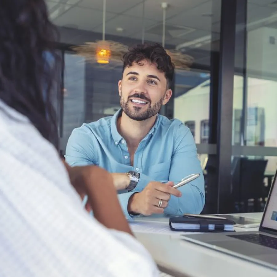 a man holding a pen and a woman looking at a laptop