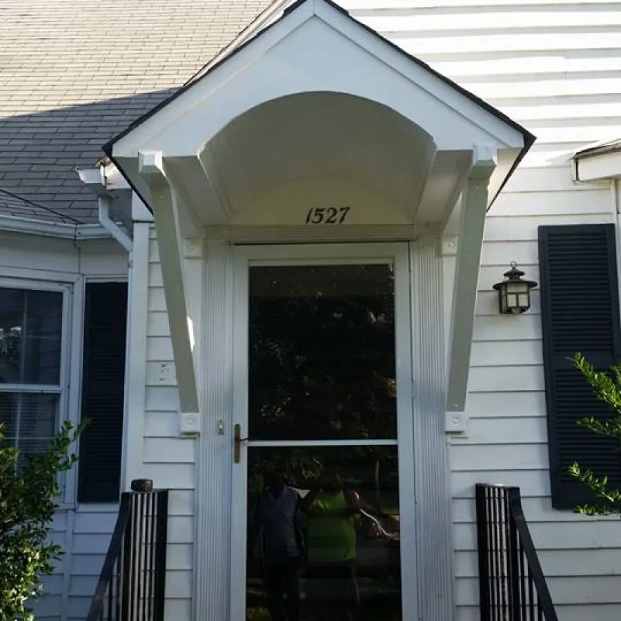 White house entrance with glass storm door, small porch, black railings, and house number 1527 above door.