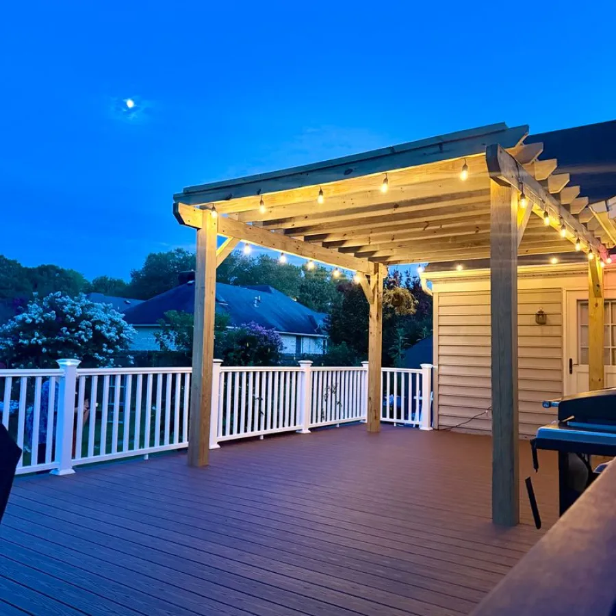 Spacious wooden deck with pergola and string lights under a clear blue evening sky and full moon.