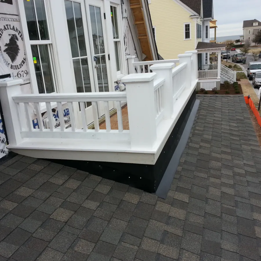 Newly constructed small white balcony on a house rooftop with shingled roof and nearby street view