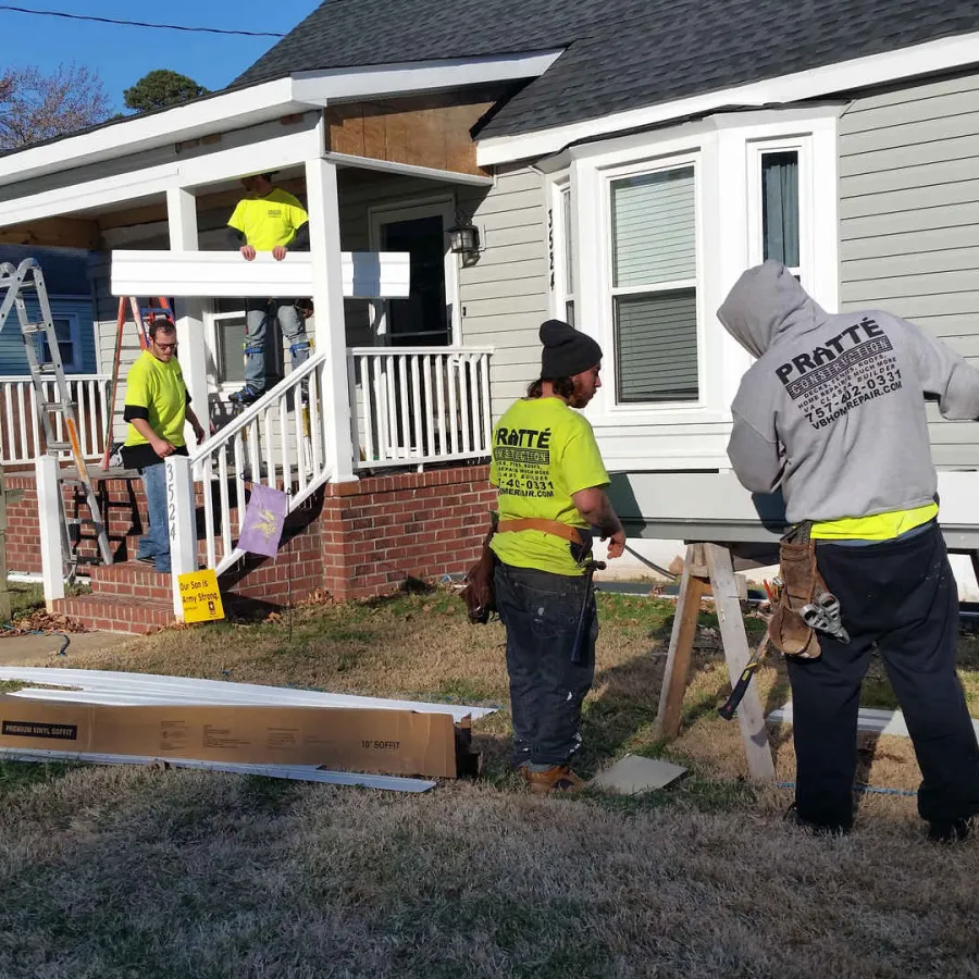 Construction workers installing or repairing a porch railing outside a residential home on a sunny day