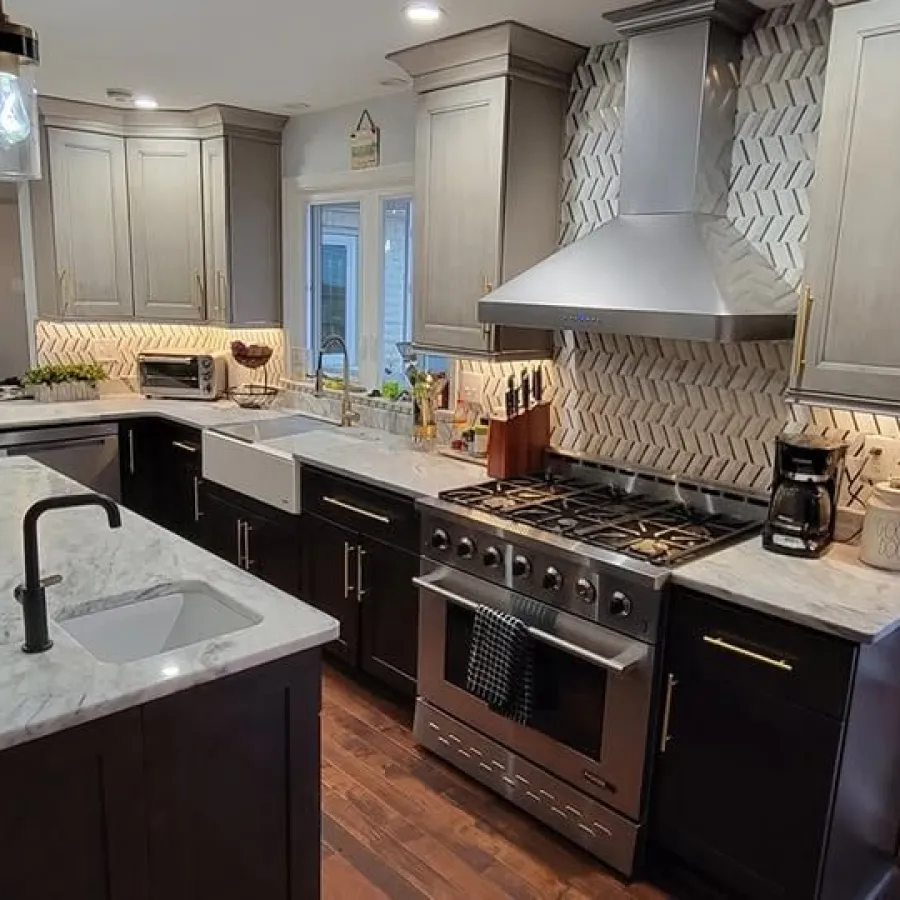 Modern kitchen with marble countertops, dark cabinets, white tile backsplash, stainless appliances, and hardwood floors.