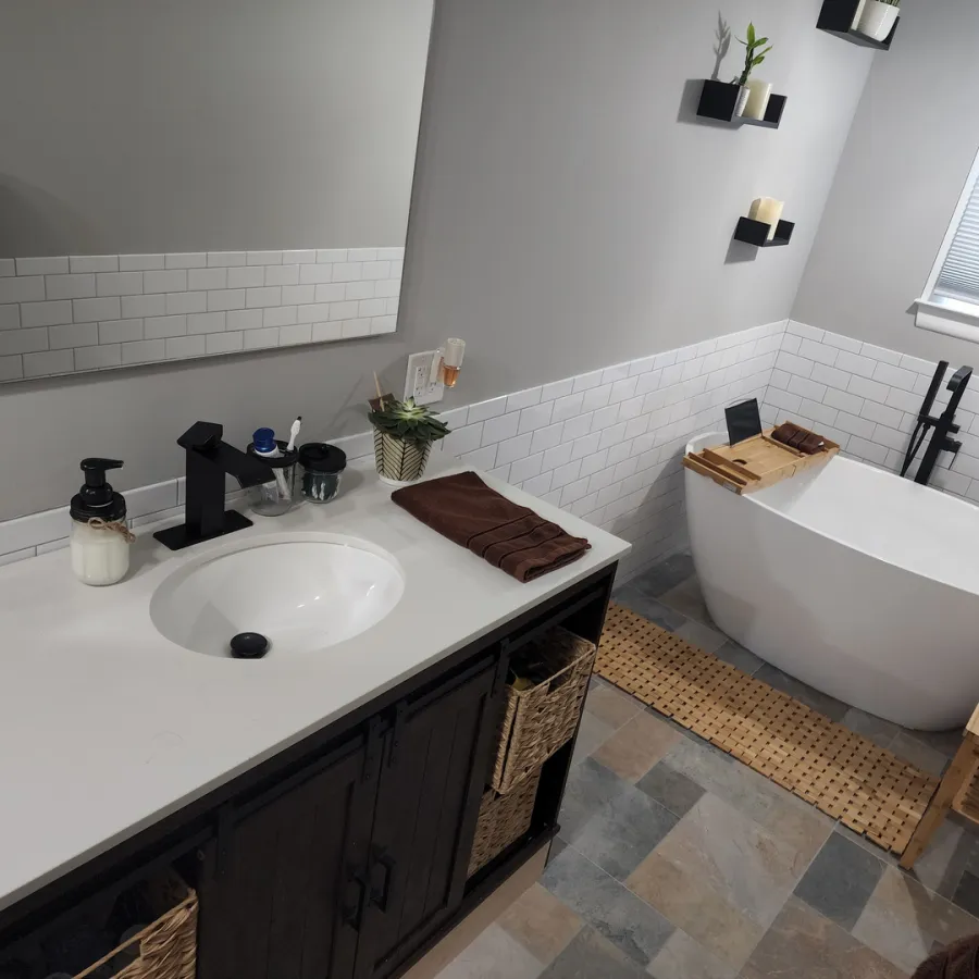 Modern bathroom with white freestanding tub, black faucet, dark vanity, and white subway tile backsplash
