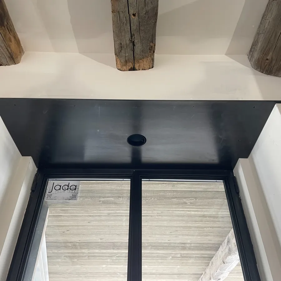 Black-framed window with wooden beams above and white walls surrounding the frame.