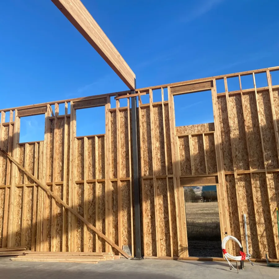 Wooden frame structure of a house under construction against a clear blue sky