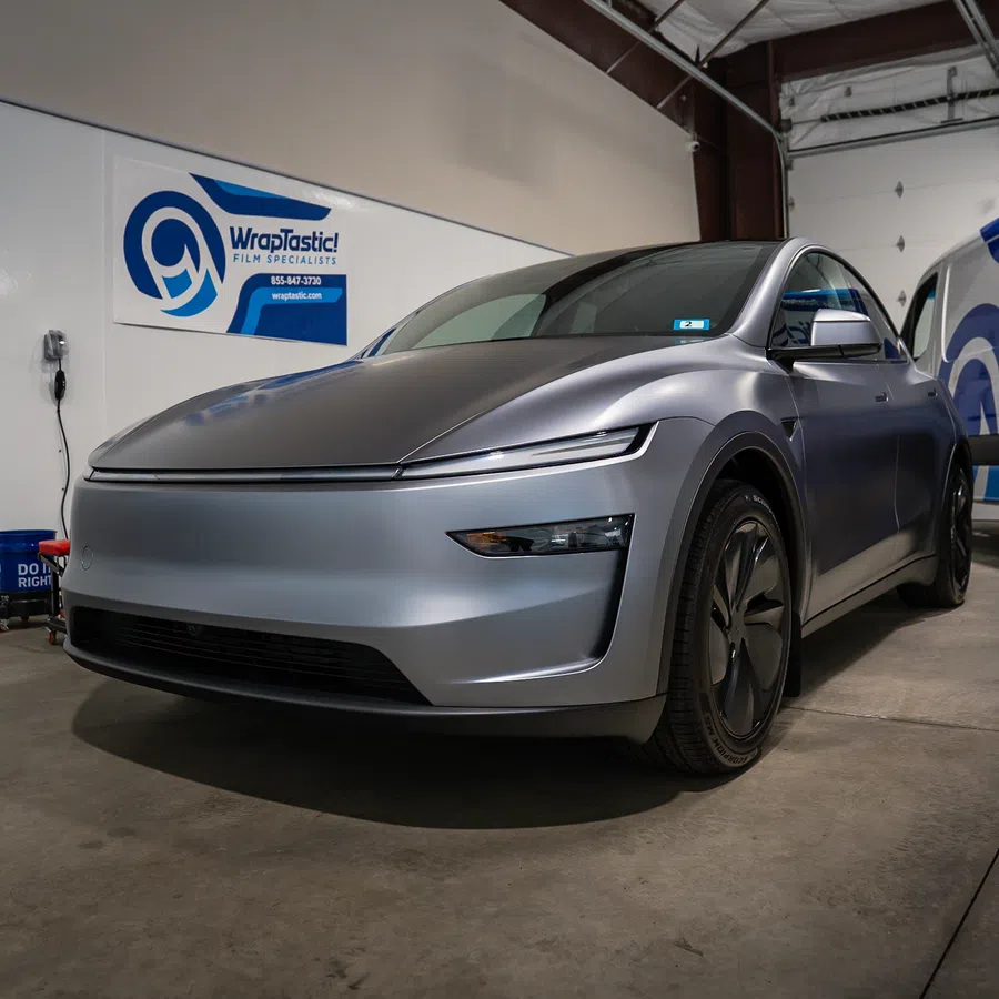 Matte silver electric car parked inside garage with WrapTastic sign in the background.
