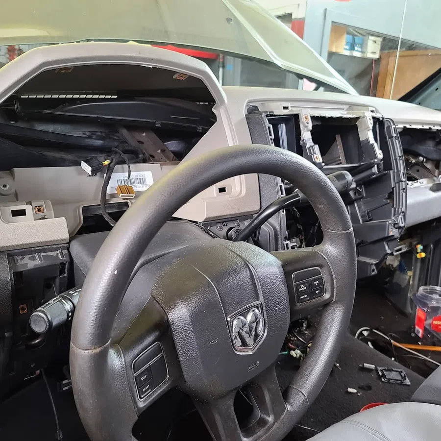 Interior of a disassembled Dodge vehicle dashboard with steering wheel and exposed wiring and components.