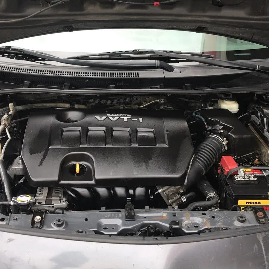 Close-up of a modern car engine bay featuring a VVT-i engine cover and battery components.