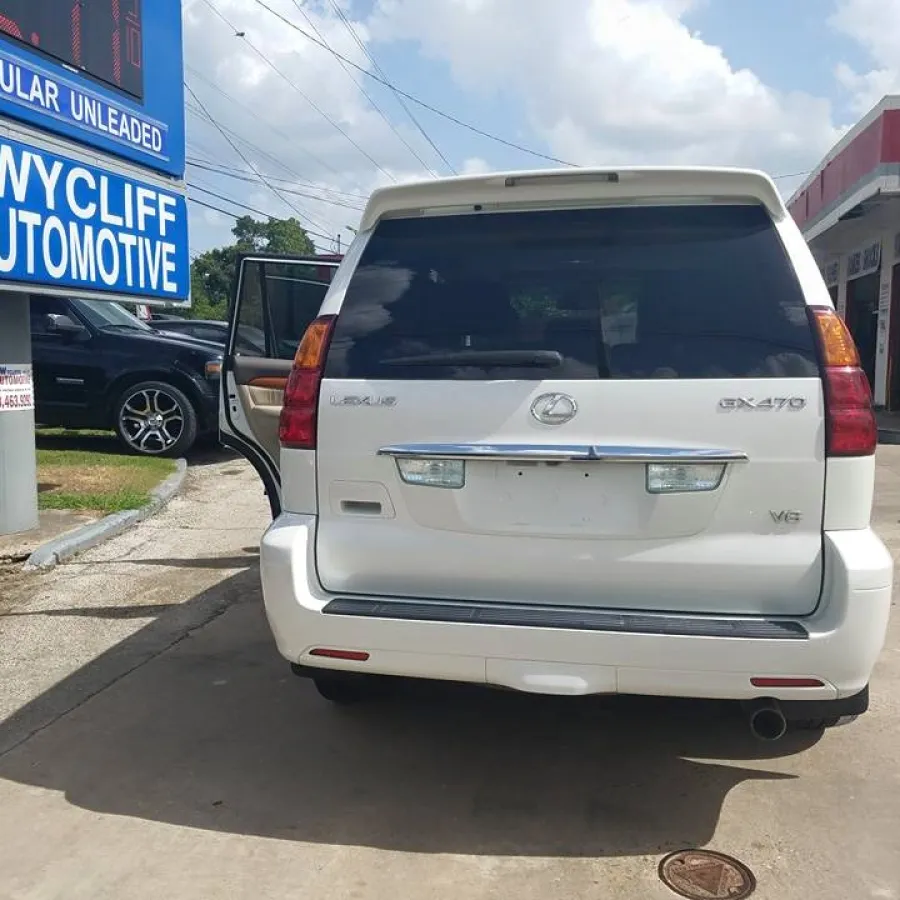 White Lexus GX470 SUV parked at Wycliff Automotive shop with open door and visible signage.