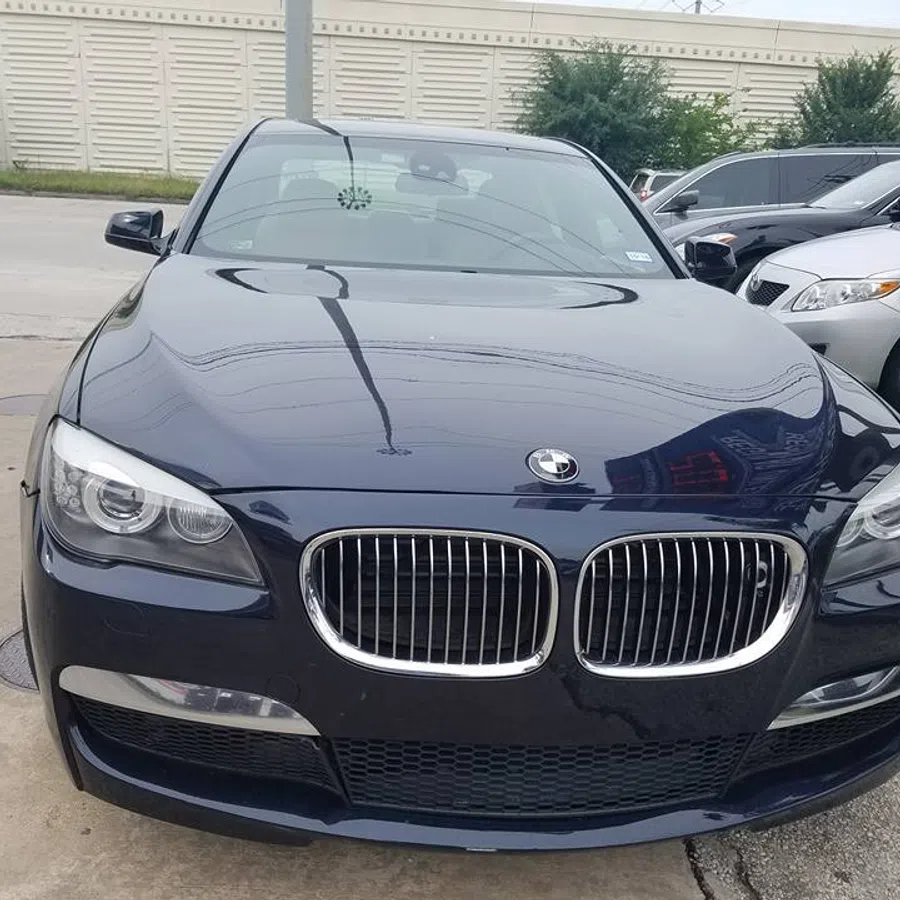 Front view of a dark blue BMW car parked outdoors showing headlights and kidney grille.