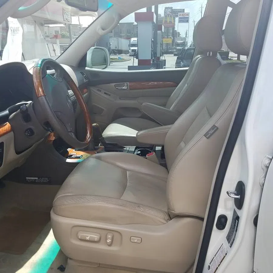 Leather front seats and wood trim interior of a white luxury car with open driver door