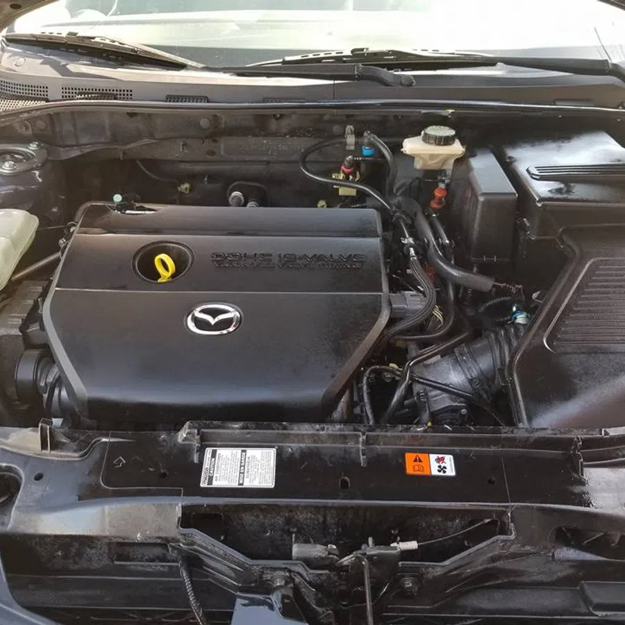 Open hood view of a Mazda car engine showcasing the clean engine cover and surrounding components.