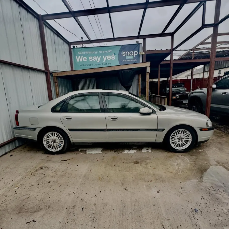 Silver sedan parked in a covered outdoor area with a financing sign in the background