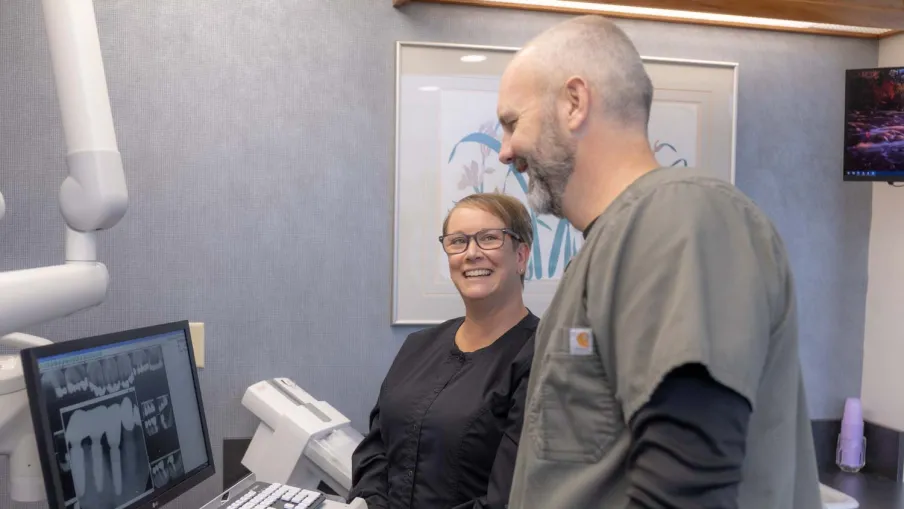 Dentists reviewing dental X-rays on a computer screen in a modern dental office setting.