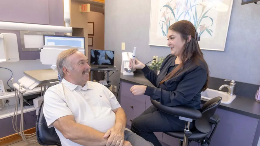 Dentist explaining dental care to a male patient in a modern dental office setting