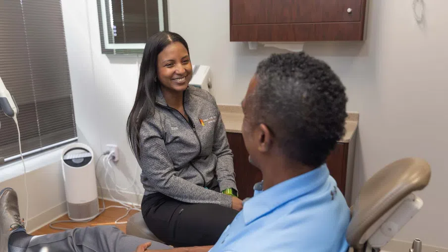 Smiling female healthcare professional consulting with male patient in a modern medical office setting.