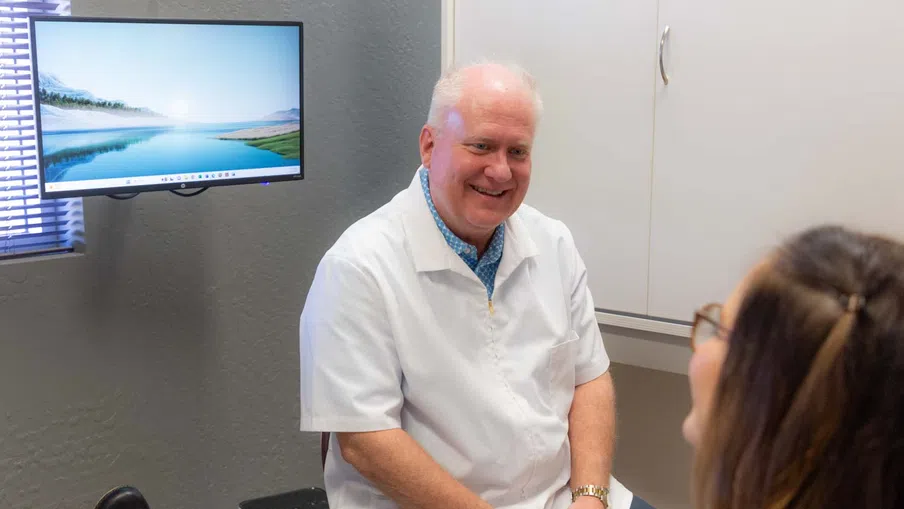 Smiling male doctor in white coat consulting a female patient in a modern medical office.