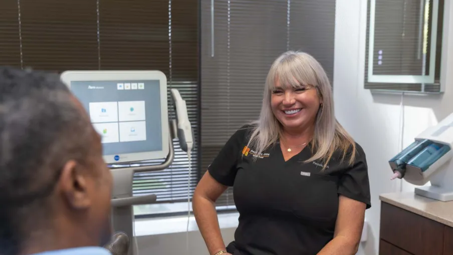 Female healthcare professional smiling and talking to a patient in a modern medical office with equipment
