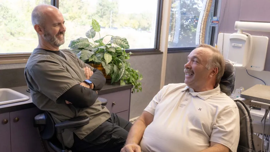 Bright modern dental clinic with dental chair, monitor, sink, and white cabinetry under natural light.