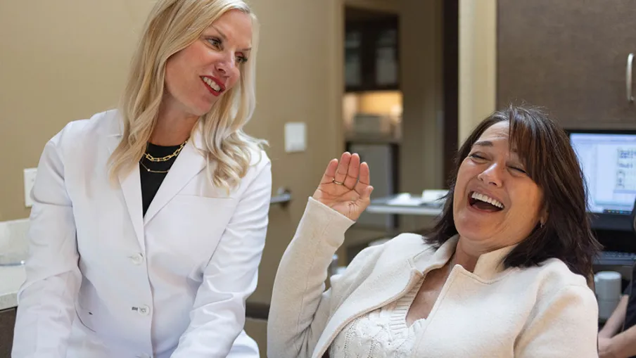 Female doctor and patient smiling and laughing together during a friendly medical appointment