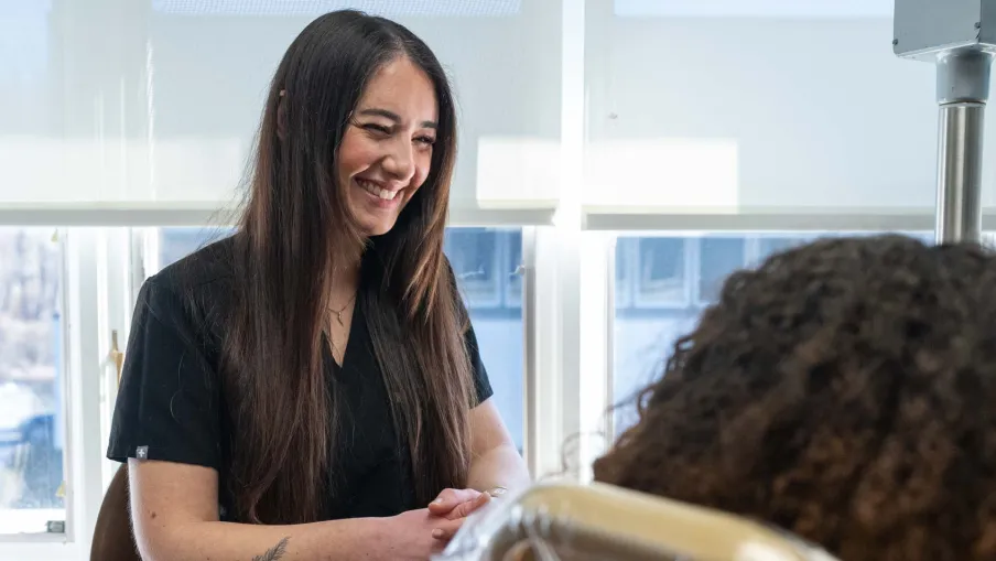 Smiling female healthcare professional talking to patient in a bright, modern medical office with natural light.