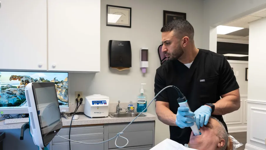 Dentist using advanced digital scanner to examine a patient's mouth in a modern dental clinic.