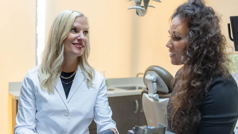 Dentist in white coat showing dental mold to patient during consultation in clinic