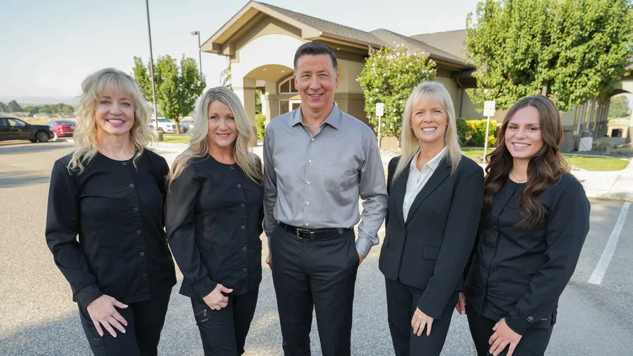 Business team of four women and one man standing outside an office building on a sunny day