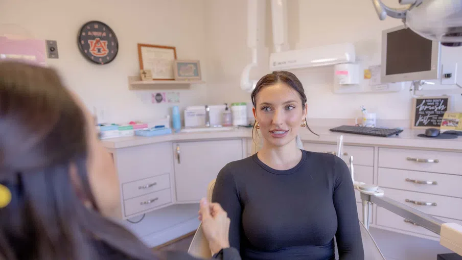 Patient consulting with dentist in a modern dental office with equipment and Auburn University clock visible