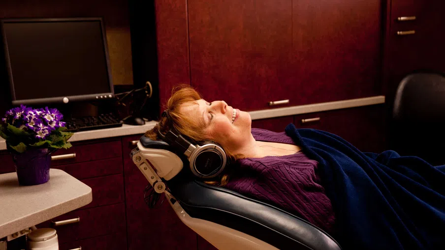 Woman relaxing with headphones on in a reclining chair covered by a blanket in a cozy room