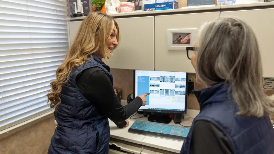 Two women reviewing medical scans on a computer screen in a clinical office environment