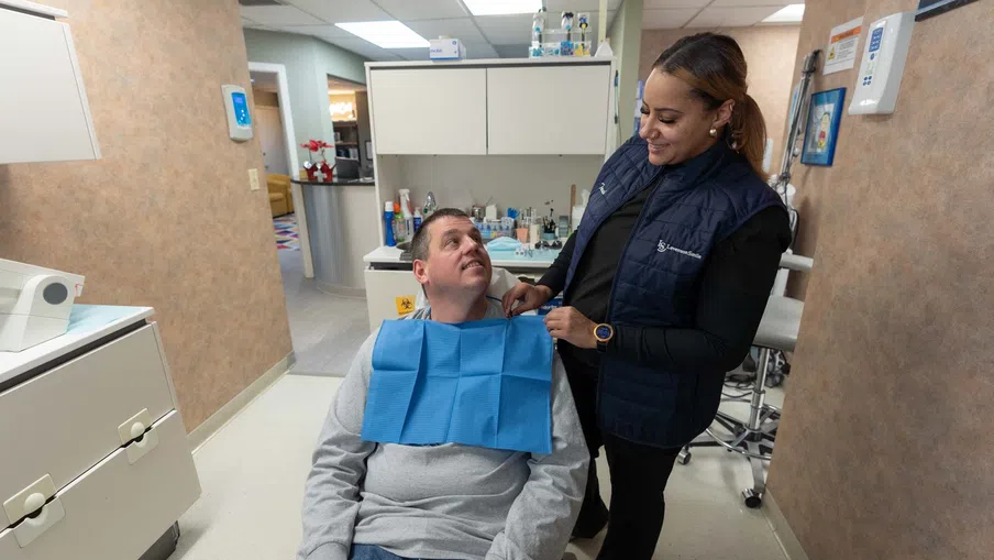 Dentist adjusts patient bib in a clean, modern dental clinic during a checkup appointment.