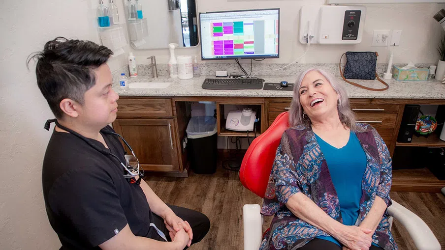 Dentist consulting with a smiling elderly woman seated in a dental chair in a modern clinic.