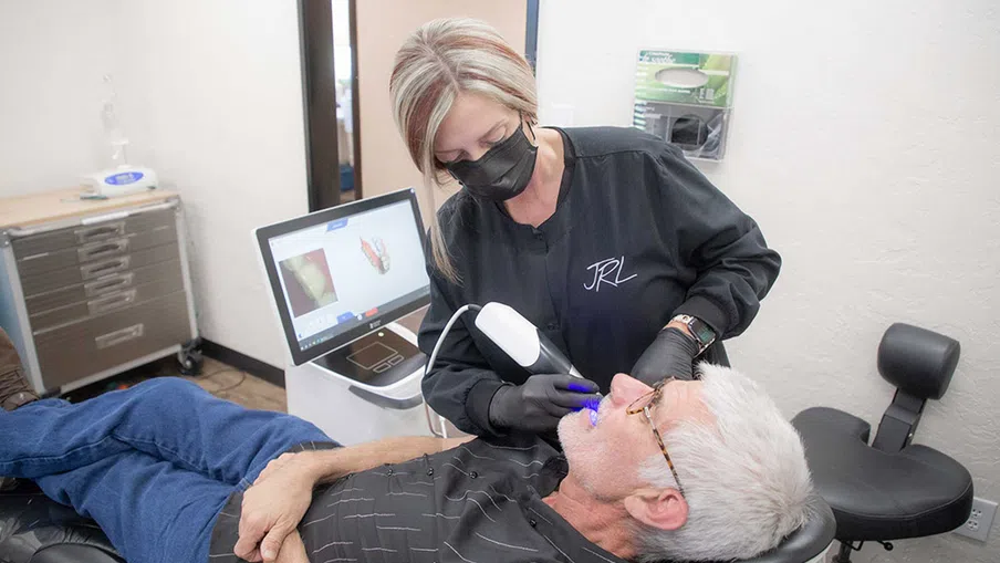 Dental professional using a digital scanner on an elderly male patient in a modern dental clinic.