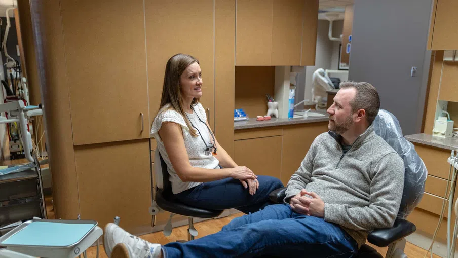 Dentist consulting male patient sitting in dental chair in a modern dental clinic interior.