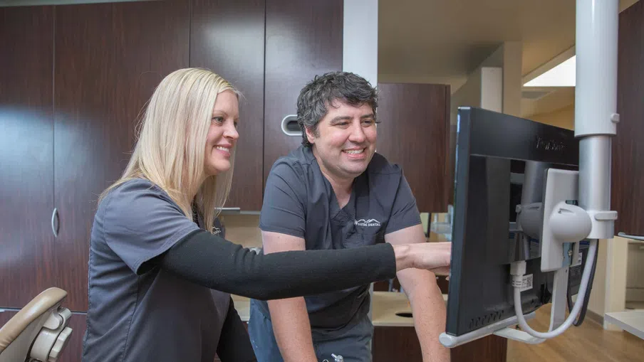 Dental professionals reviewing patient information on computer screen in a modern dental office.