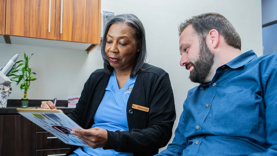 Female doctor reviews medical information with male patient in a modern clinic office setting.