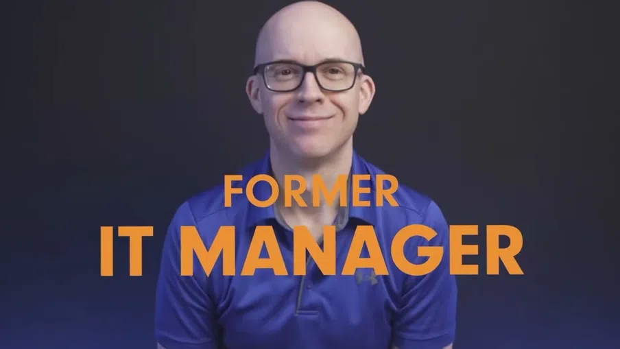 Smiling bald man in glasses wearing blue shirt with text Former IT Manager in orange on dark background