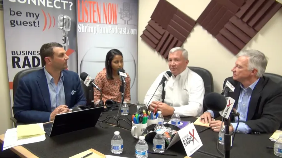 a group of people sitting at a table with microphones