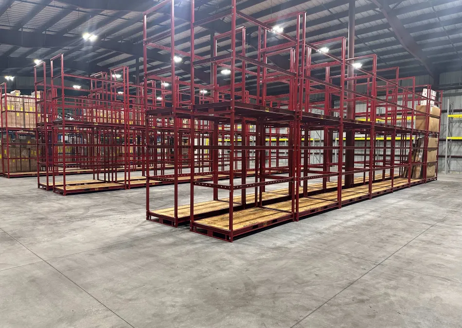 Large empty red metal storage racks inside a spacious industrial warehouse with concrete flooring and high ceiling.