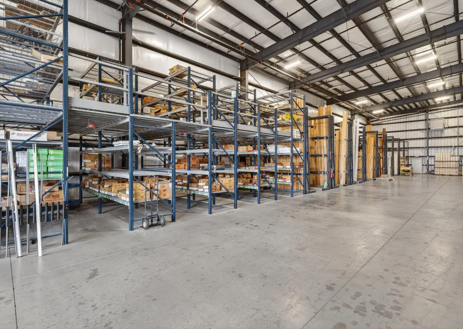 Spacious organized warehouse with metal shelving stocked with boxes and materials under bright industrial lighting.