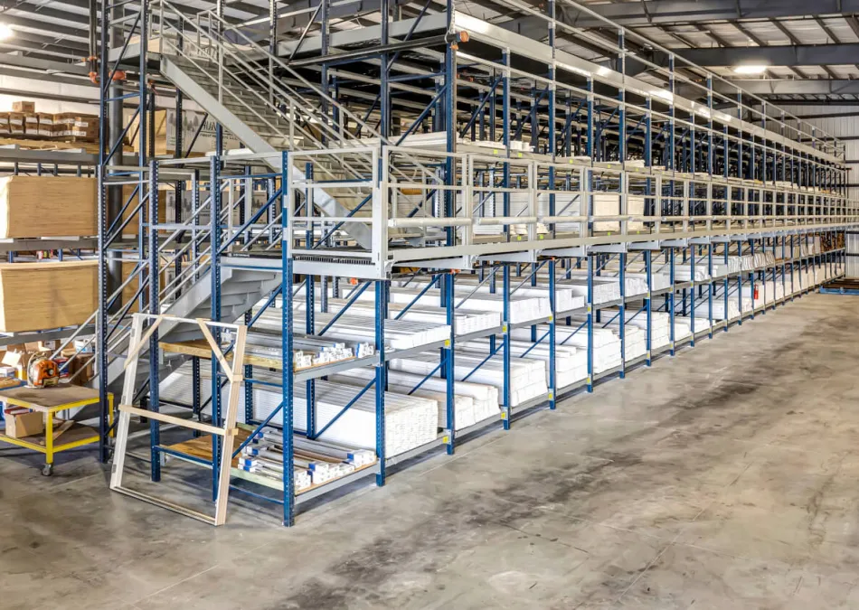 Spacious warehouse interior with metal shelving, stacked materials, and a forklift on concrete floor.