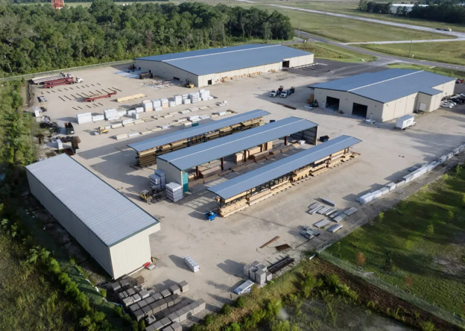 Aerial view of an industrial lumber yard with multiple storage buildings and stacks of wood materials.