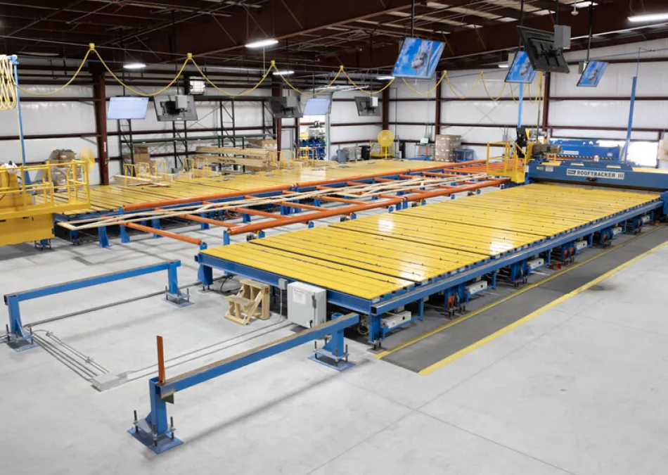 Large automated industrial machine with yellow and blue components inside a spacious manufacturing facility.